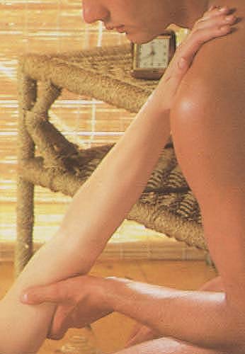 Zachte strijkende massage van de triceps bovenarm spier met de volle linkerhand, hand steunt op de schouder. Detail foto.