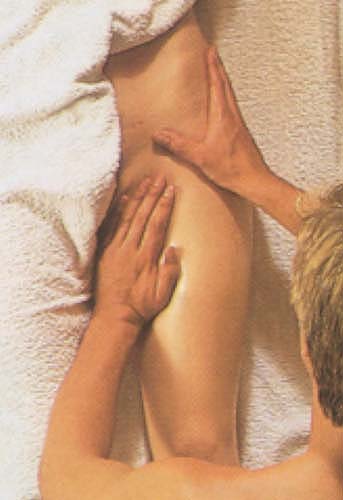 Bij de sensuele massage van de grote dijbeenspier masseren de handen de liesstreek en de zijkant van het bekken. Detailfoto